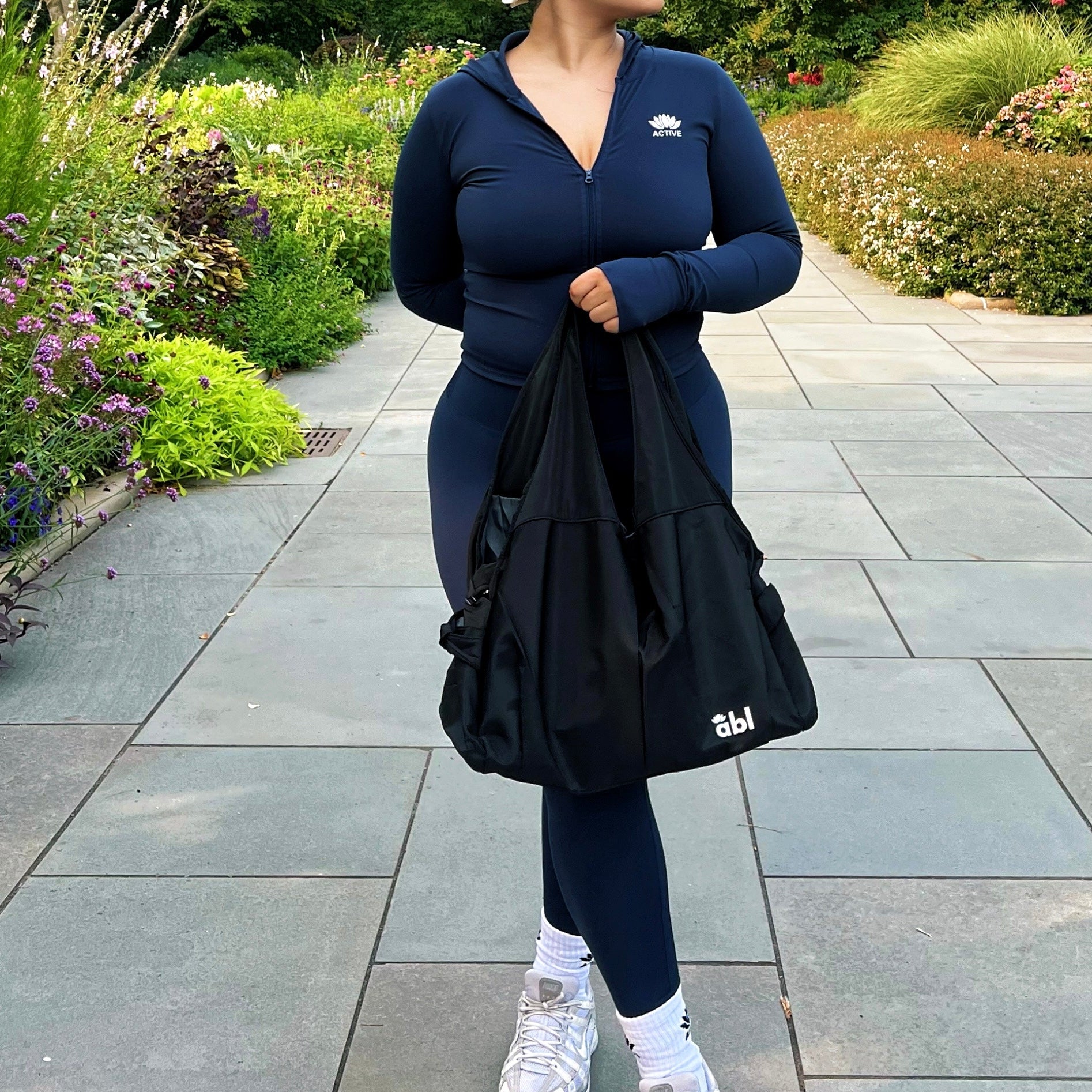 Person wearing a navy blue outfit with white sneakers in a garden setting